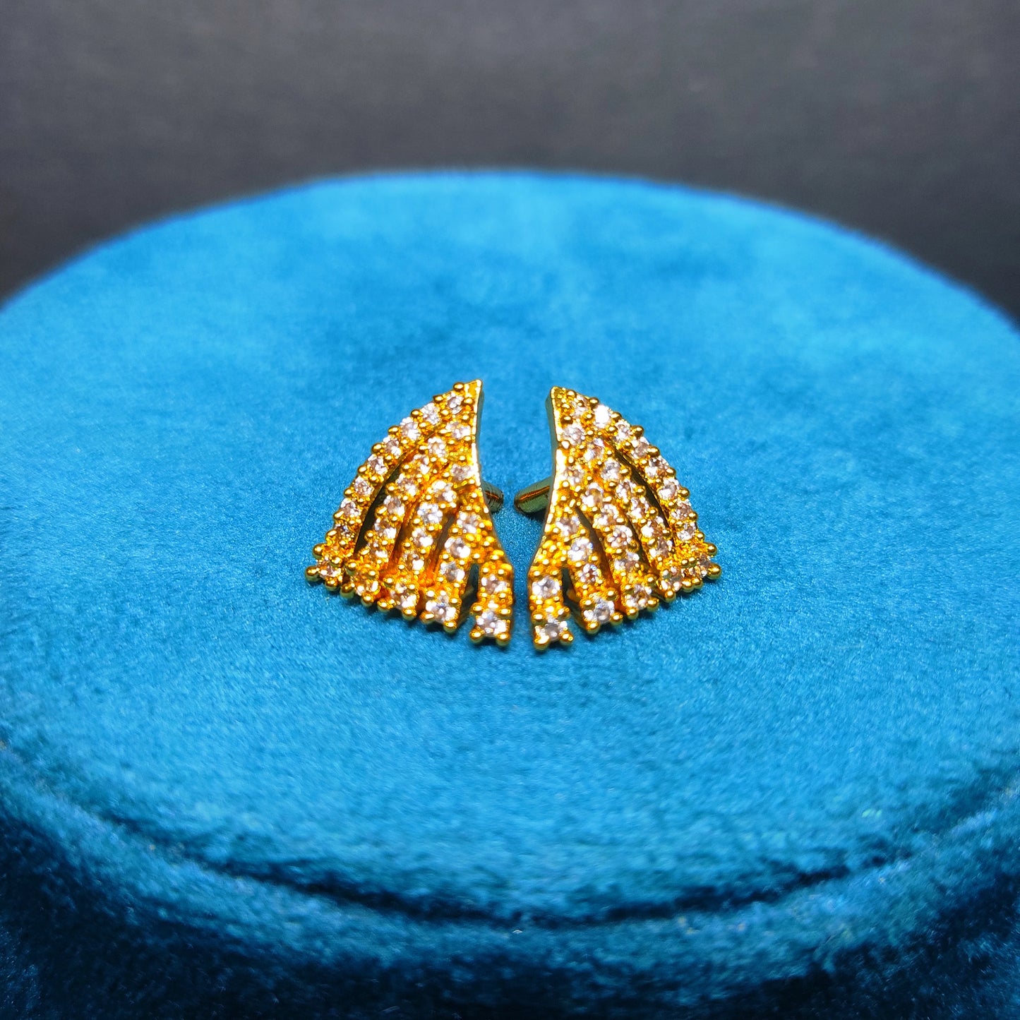 Gold plated earrings with gemstones on a blue cushion