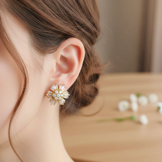 Close-up of a person wearing a gold plated floral earring with a blurred background