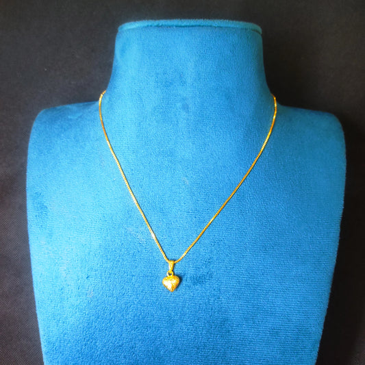 Gold plated neckchain with a heart pendant on a blue mannequin bust against a black background