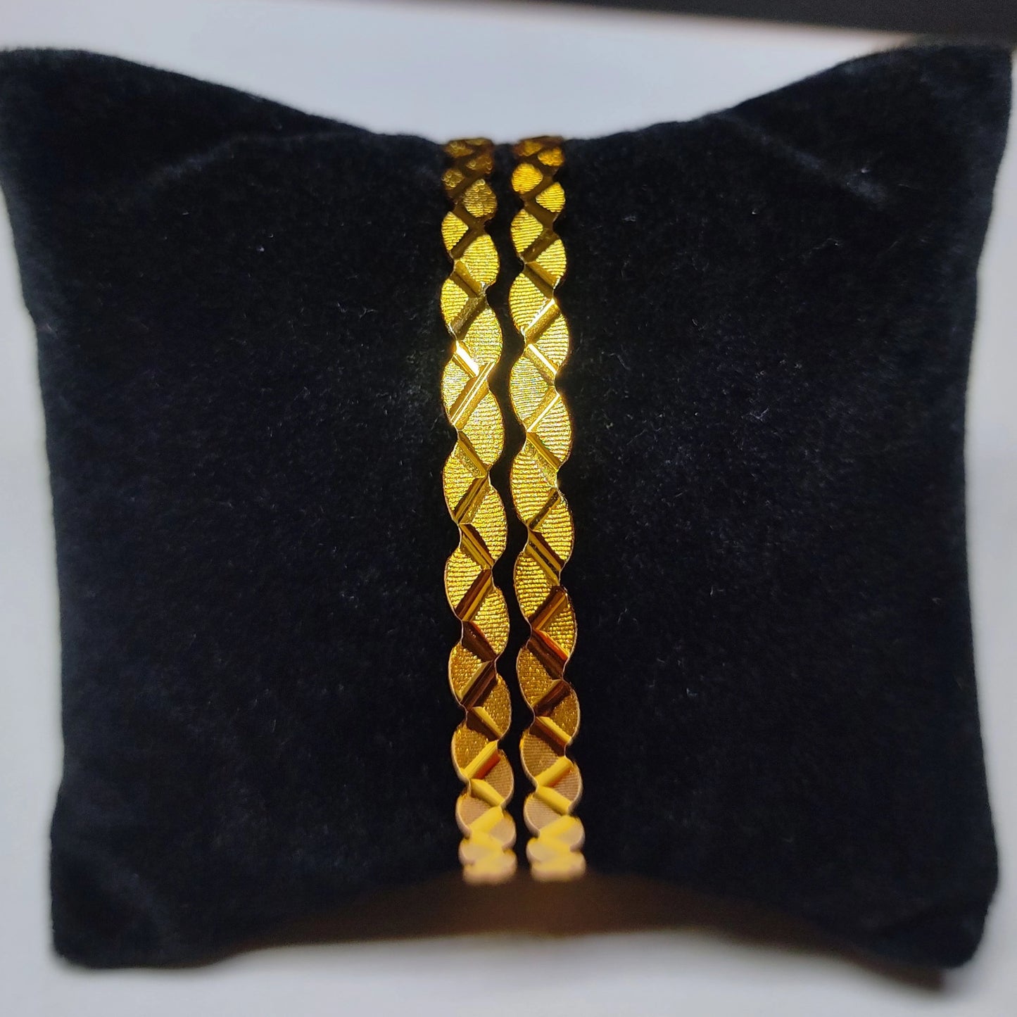 Gold plated bangles on a black velvet cushion