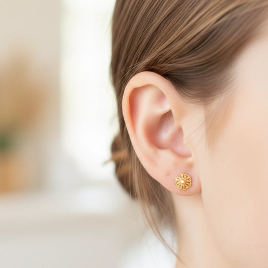 Gold plated earring worn by a person with a blurred background