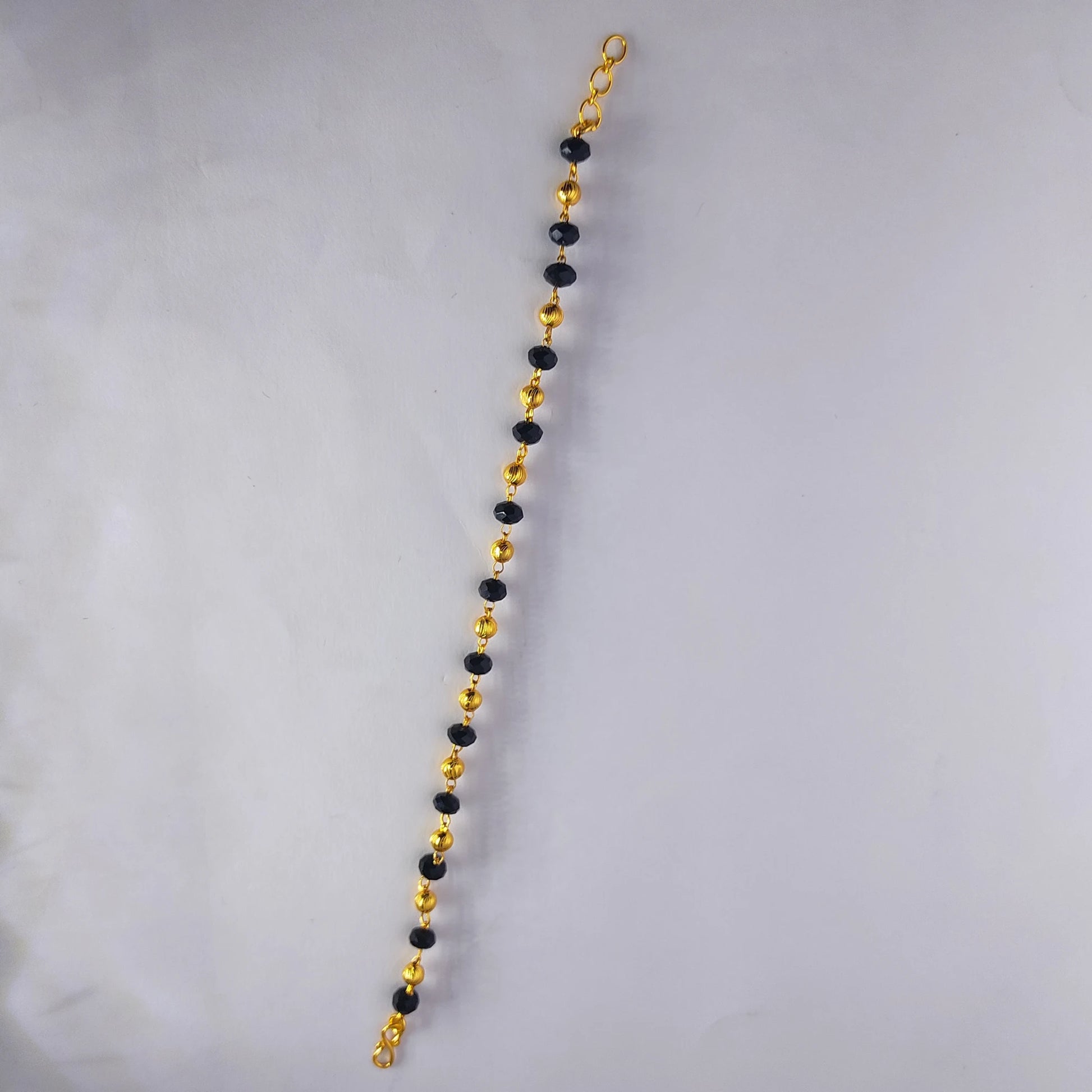 Gold and black beaded gold plated bracelet on a gray background