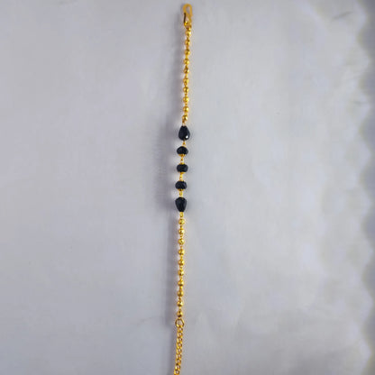 Gold plated bracelet chain with black beads on a white background