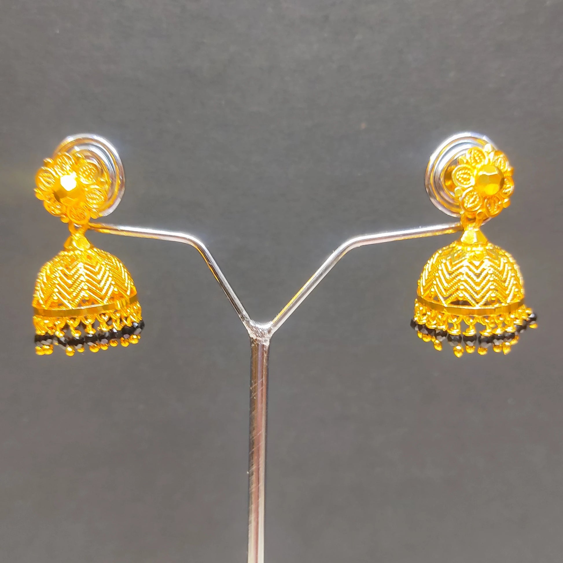 Gold plated traditional Jimikki/Jhumka with black beads earrings on a gray background