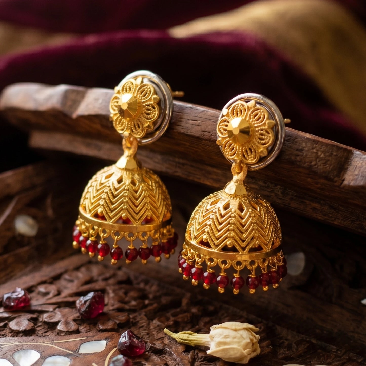 Gold plated Traditional Jimikki/Jhumka earrings with red beads on a wooden surface