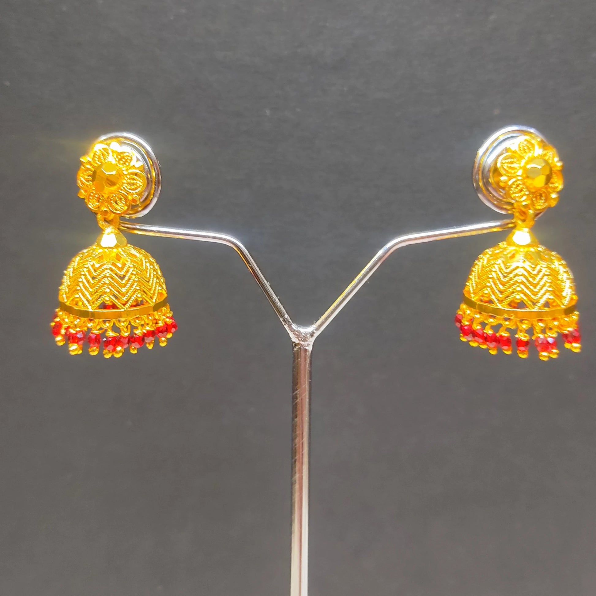 Gold plated traditional Jimikki/Jhumkas with red beads earrings on a gray background