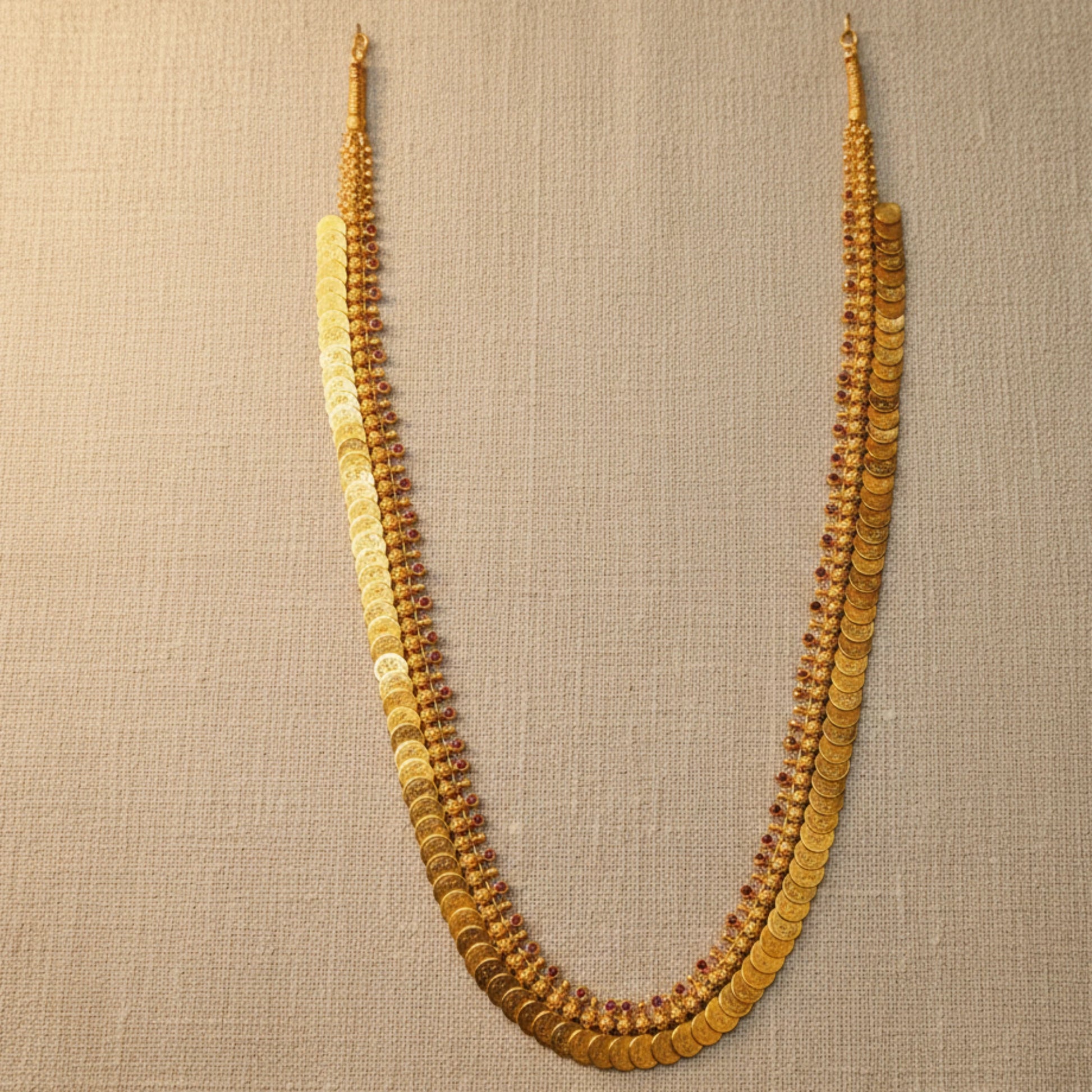 Gold plated necklace with multiple strands on a beige fabric background