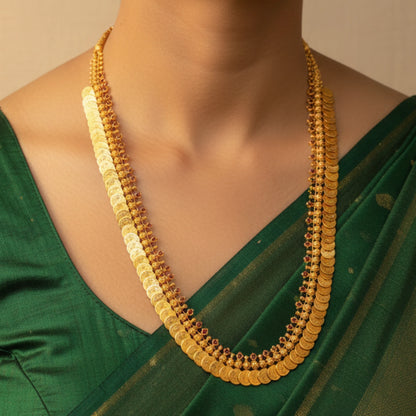 Gold plated Kasu mala necklace on a person wearing a green saree against a beige background