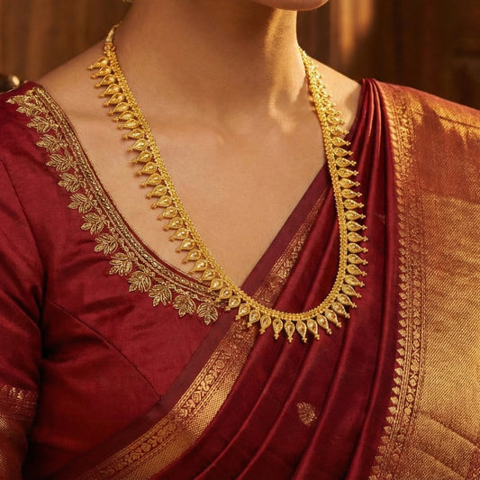 Red saree with gold embroidery and a matching gold-plated necklace.