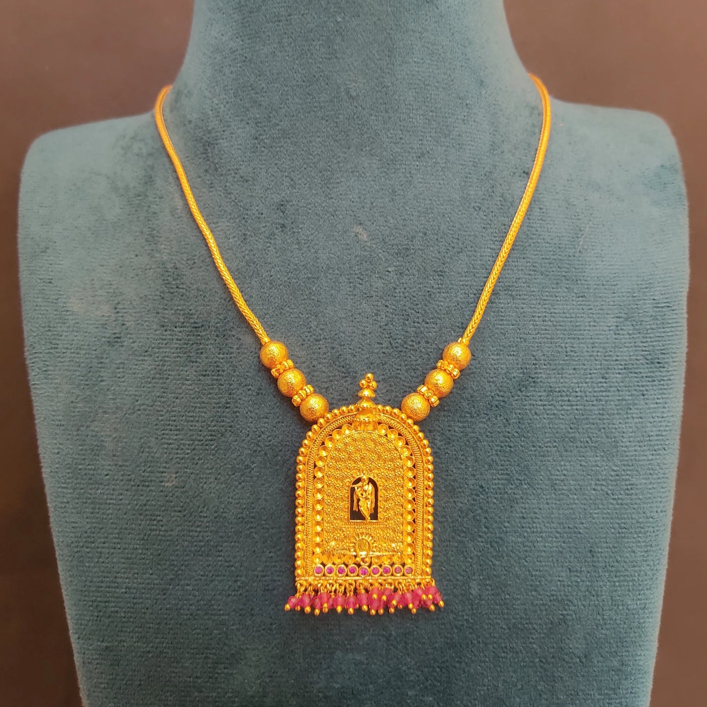 Gold Plated Traditional Krishna Temple Arch necklace with a pendant on a green mannequin