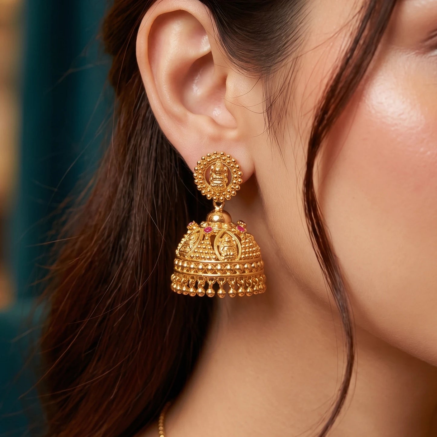 Close-up of a person wearing a gold plated Traditional Lakshmi Heritage Jimikki/Jhumka earring with intricate design