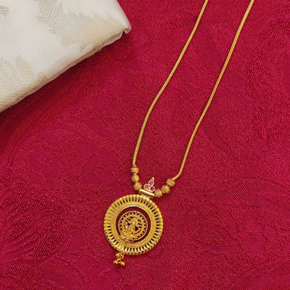Gold plated necklace with a circular pendant with Lakshmi Motif on a red fabric background