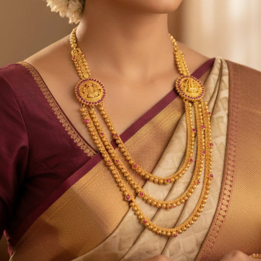 Gold plated Lakshmi Haram necklace with red stones worn by a person in a traditional outfit