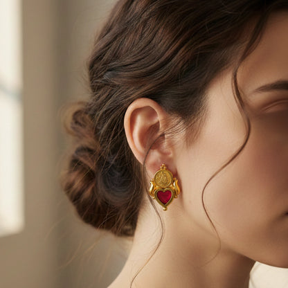 Close-up of a woman wearing a gold plated palakka heart earring with a ruby red inlay