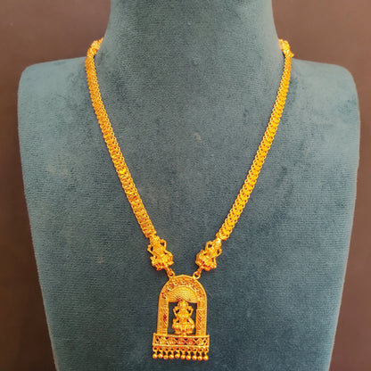 Gold plated necklace with a temple arch lakshmi pendant on a green mannequin against a brown background