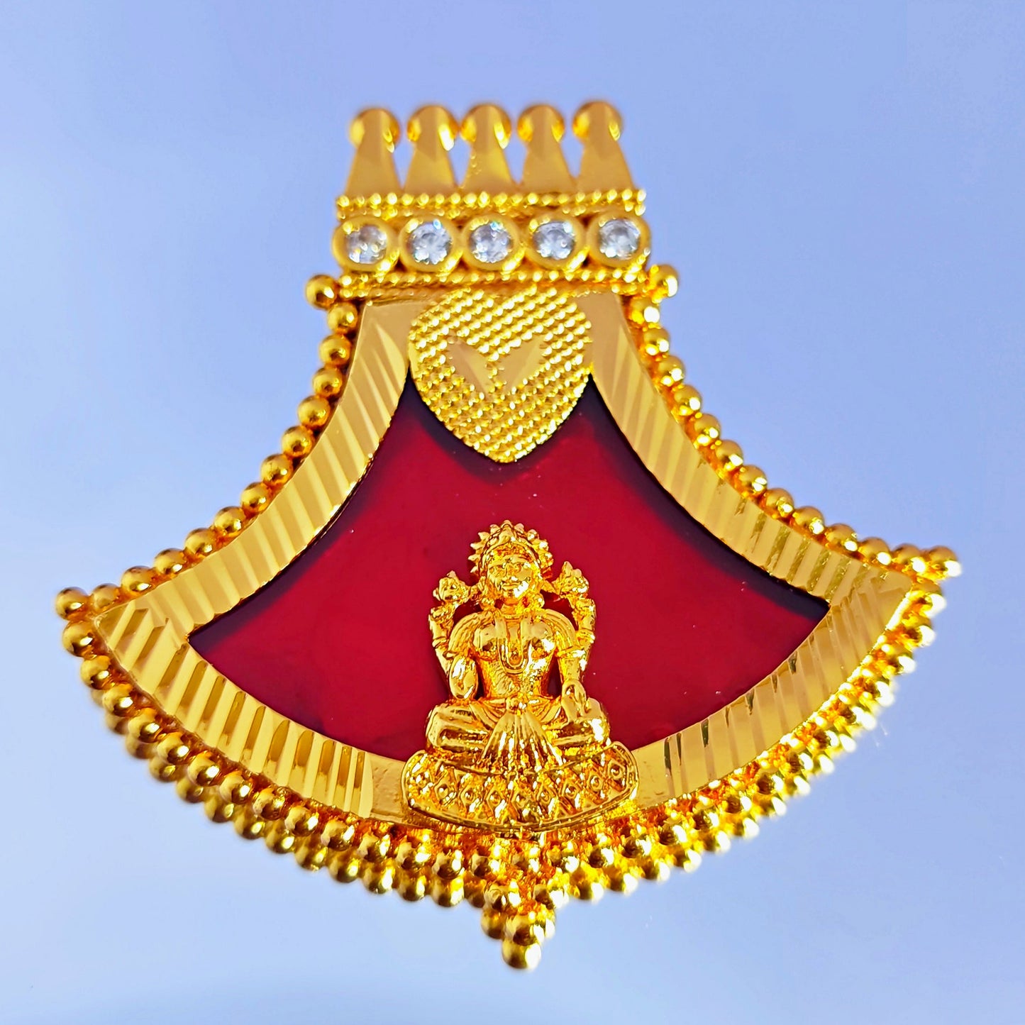 Gold plated Pendant withred decorative item with a central figure on a blue background