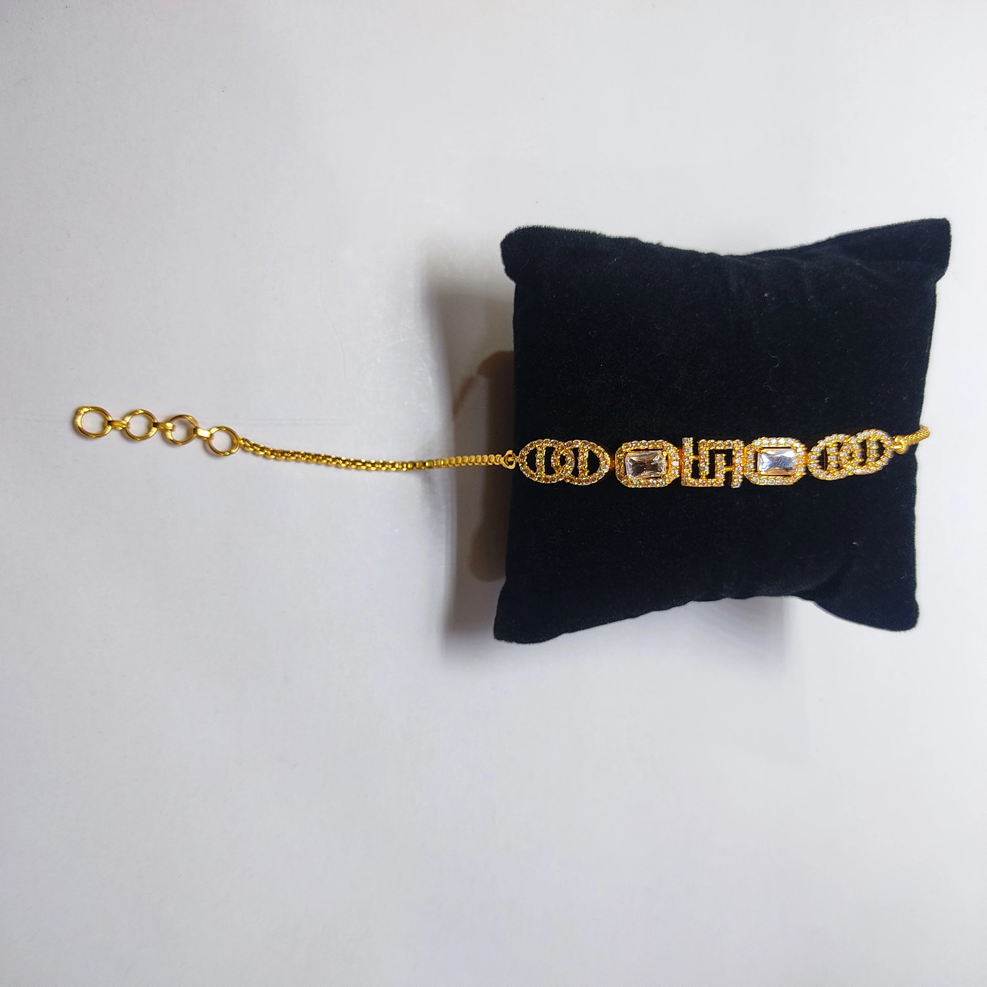 Gold plated bracelet on a black velvet cushion against a white background