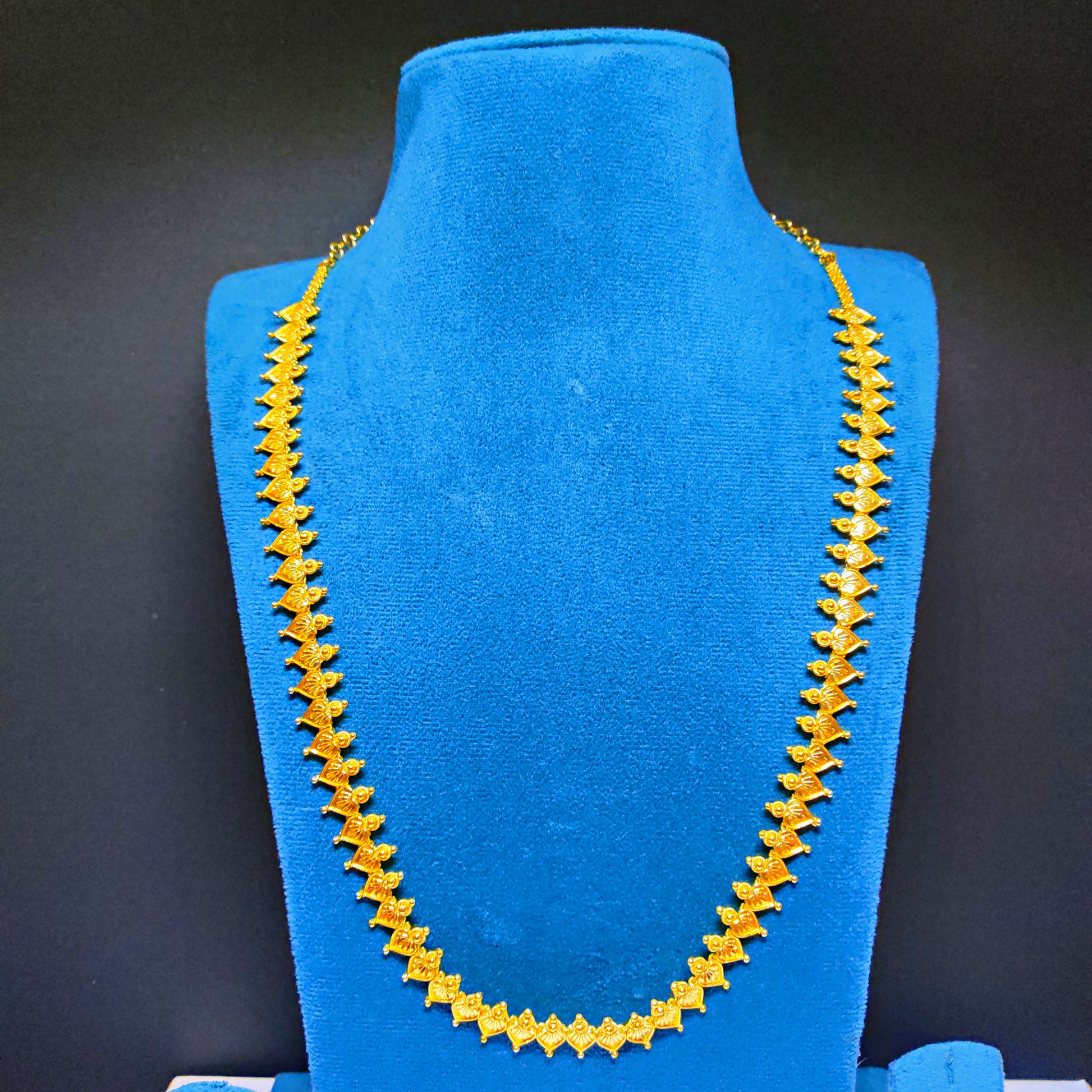 Gold plated necklace on a blue mannequin bust against a black background