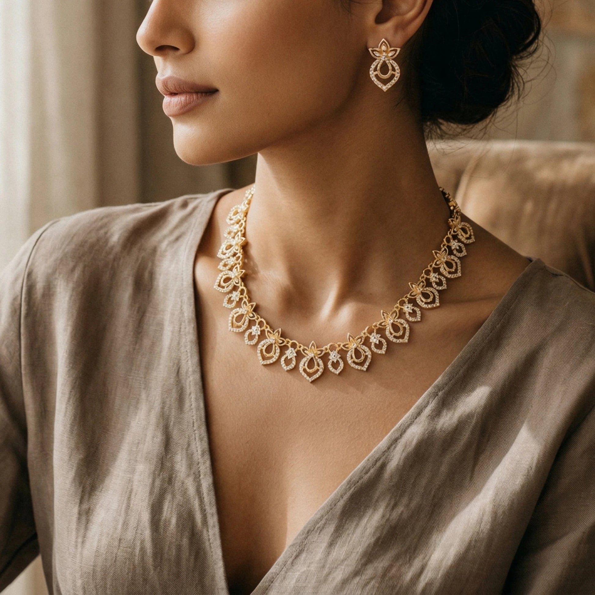 Woman wearing a gold toned AD necklace and earrings with a neutral background