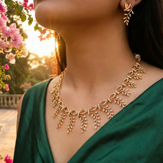 Woman wearing a gold toned necklace and earrings with a blurred floral and sunset background
