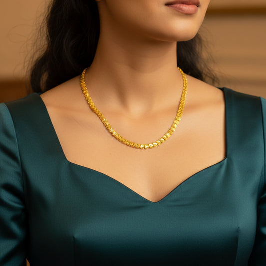 Woman wearing a gold plated neckchain with scalloped link pattern with a blurred background