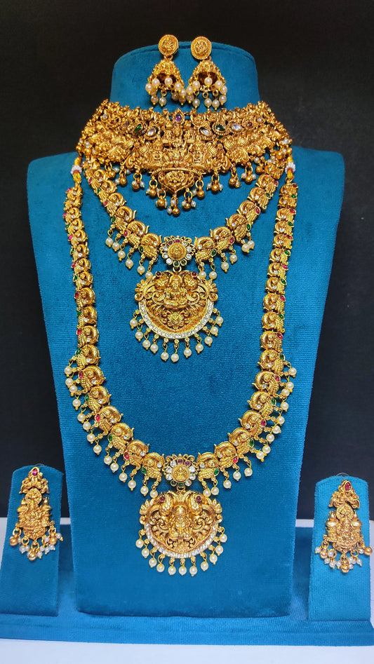 Antique Gold Finish set of necklaces, choker and earrings set on a blue stand against a black background