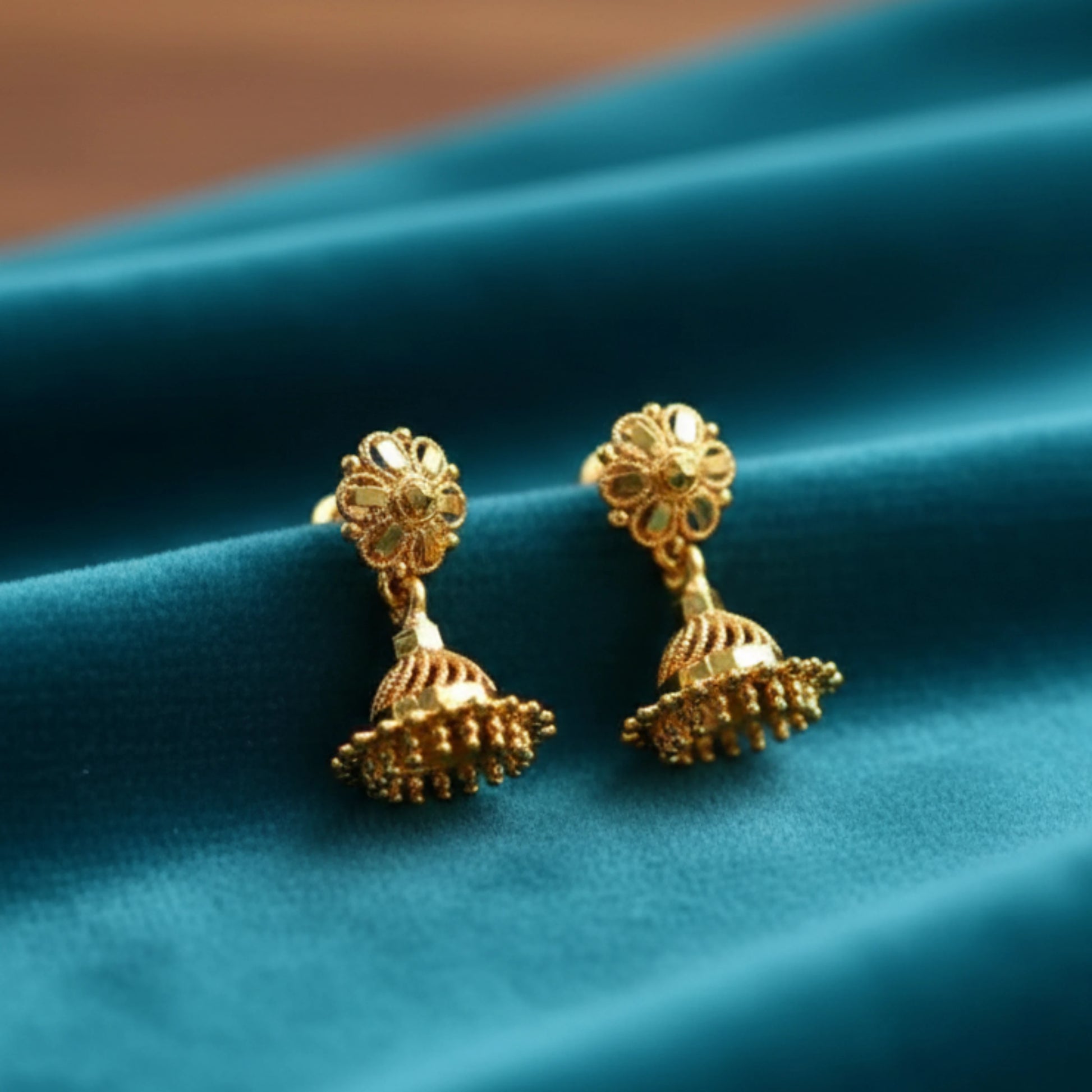Gold plated earrings on a blue fabric background