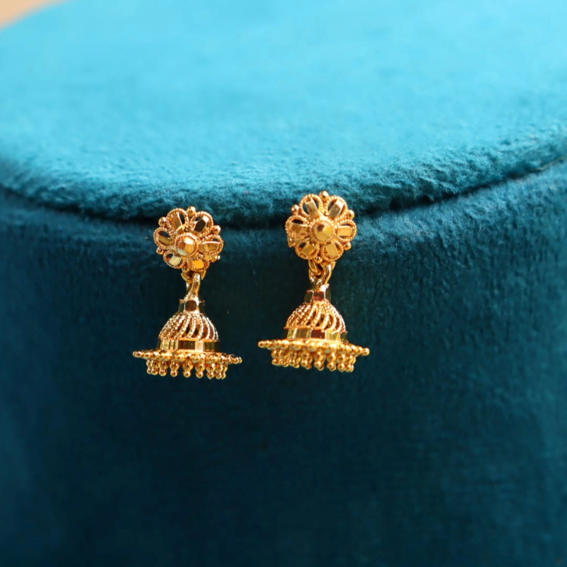 Gold plated earrings on a blue velvet background