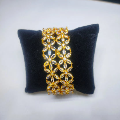 Gold toned bangles with floral design on a black cushion
