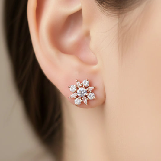 Close-up of a person wearing a rose gold snowflake-shaped Ad Stones earring.