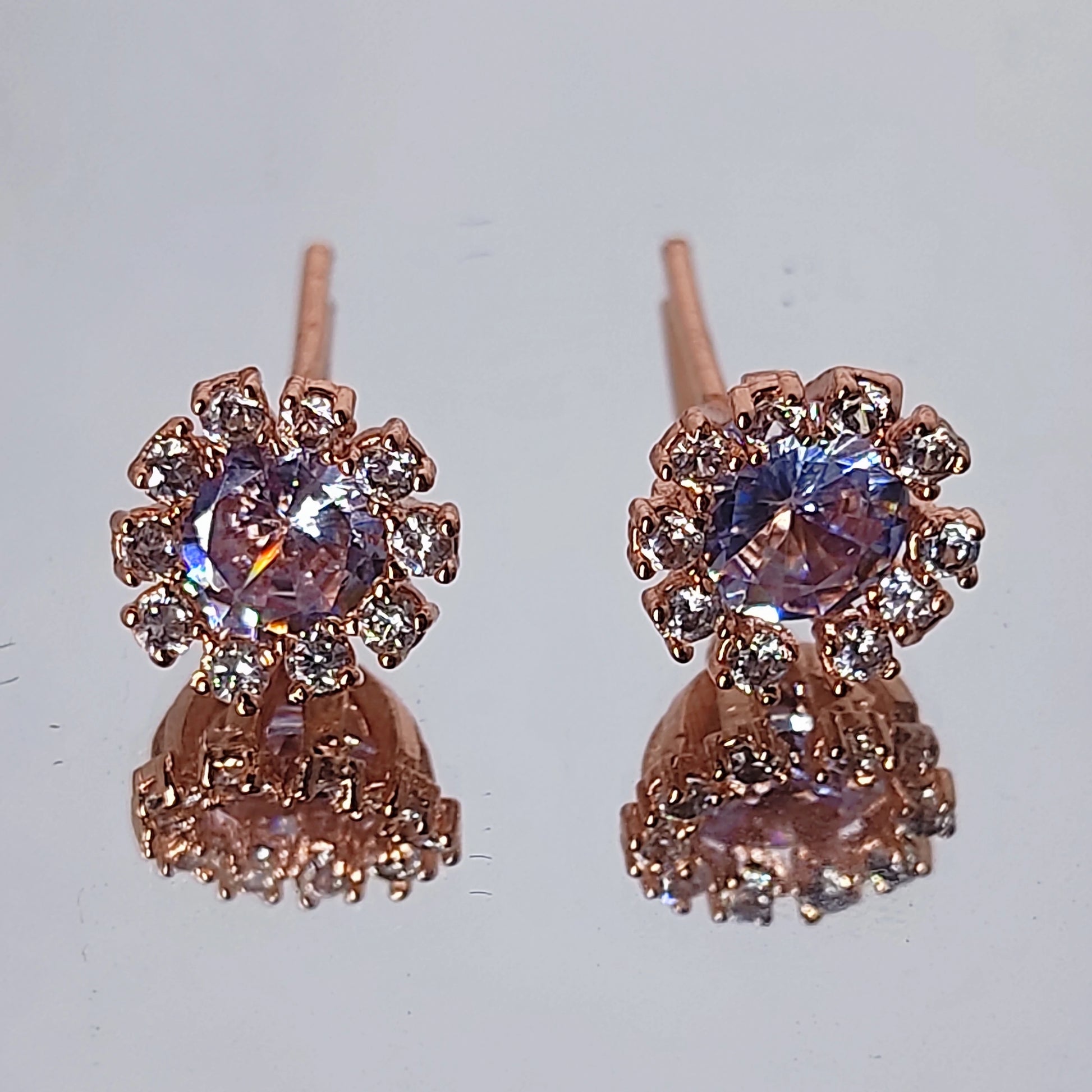 Rose Gold Plated Dainty Lavender Hue Earrings in AD stones on a reflective surface