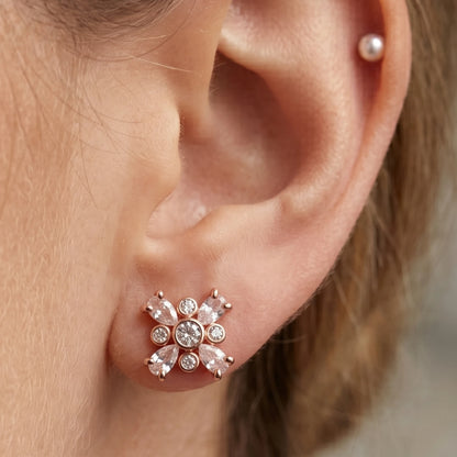 Rose gold flower stud earrings with marquise cut stones on a model's Ear