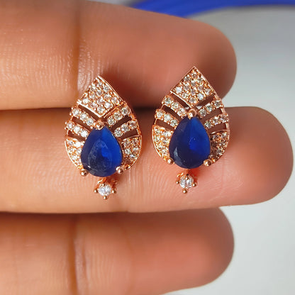 Teardrop-shaped sapphire earrings with rose gold setting on a finger