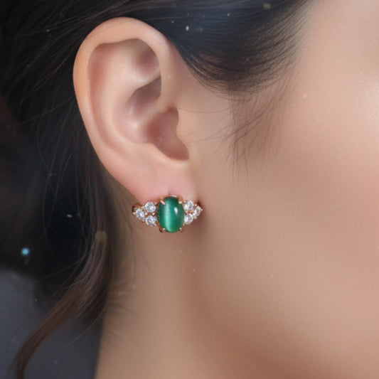 Close-up of an ear wearing a green gemstone earring with a blurred background