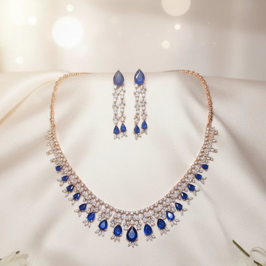 Rose Gold Jewelry set with necklace and earrings featuring blue stones on a soft white background