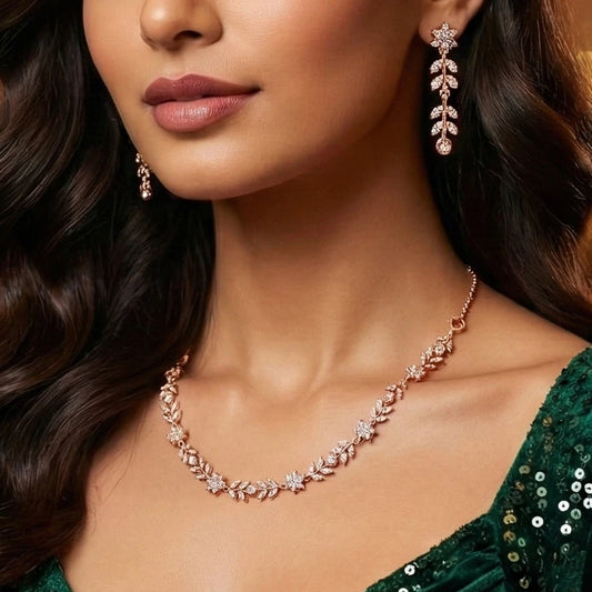 Close-up of a woman wearing a rose gold necklace and earrings with a green dress.
