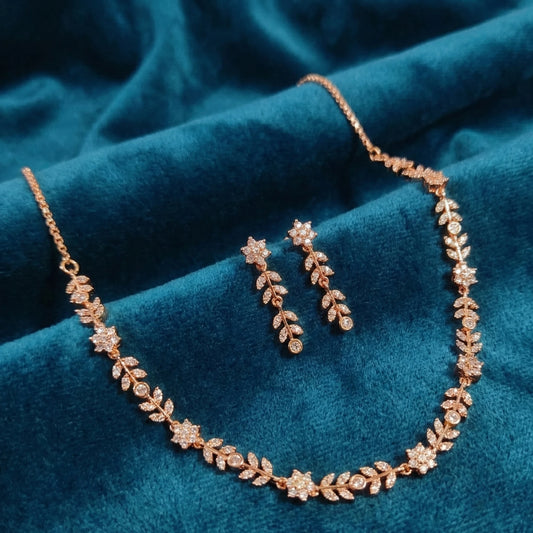 Rose gold jewelry set with necklace and earrings on a blue fabric background