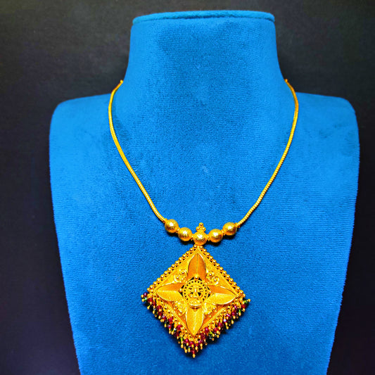 Gold plated necklace with a decorative pendant on a blue mannequin against a black background
