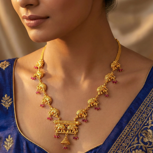 Gold plated necklace with elephant designs worn by a person in a blue traditional outfit.