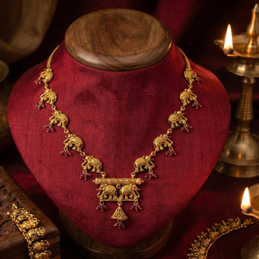 Gold plated necklace with elephant designs on a red velvet stand