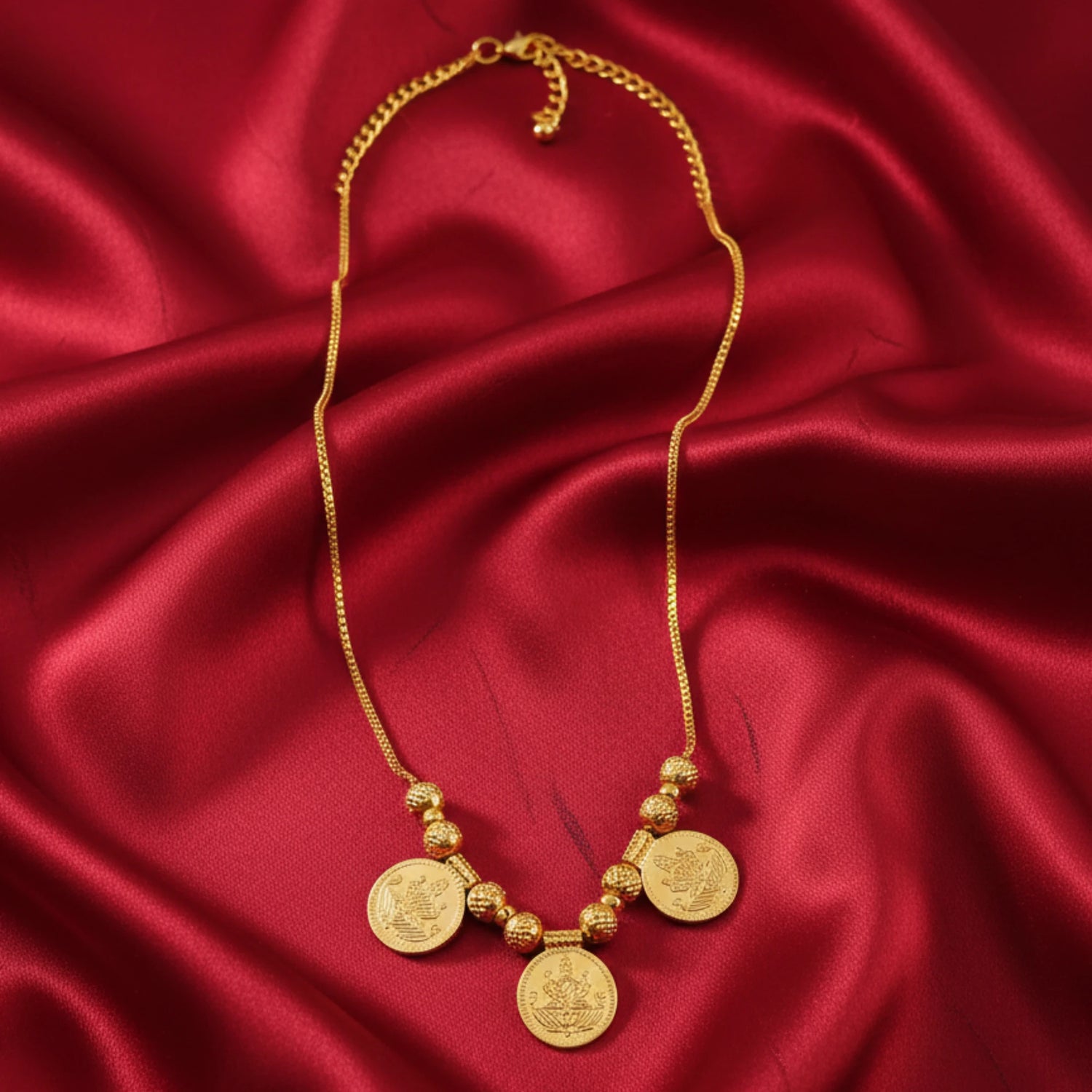 Gold Plated Tiny Lakshmi coin necklace for kids displayed on a red satin cloth