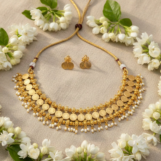 Antique Gold Finish Kaasumala necklace and earrings with white flowers on a beige fabric background
