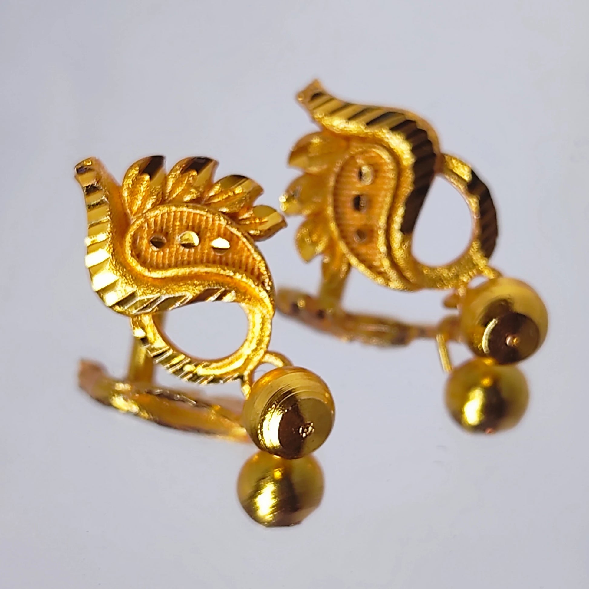 Gold plated manga mani earrings with intricate designs on a light gray background