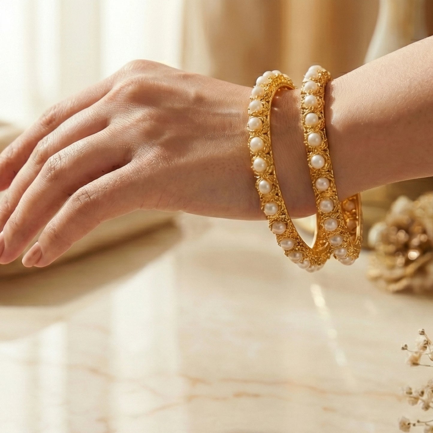 Gold plated with pearls Bangles on a hand with a soft background