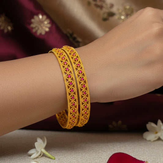 Gold plated bangles with pink stones on a wrist, with a blurred background