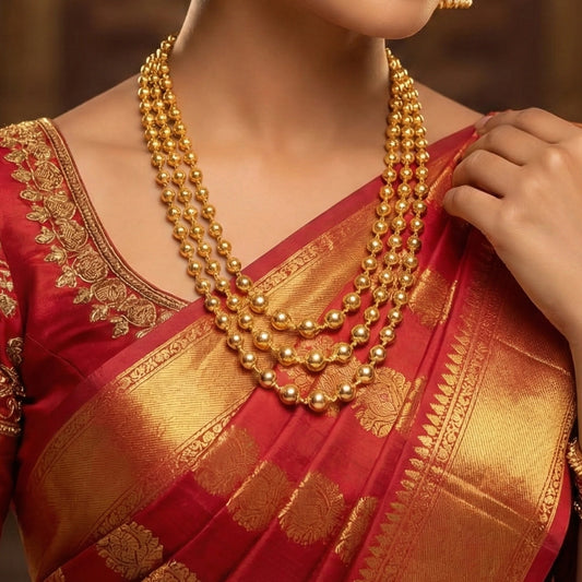 Red saree with gold patterns and a person wearing a gold plated necklace.
