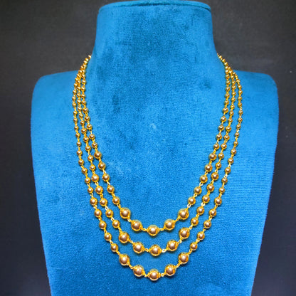 Gold plated 3 layered beaded necklace on a blue velvet stand