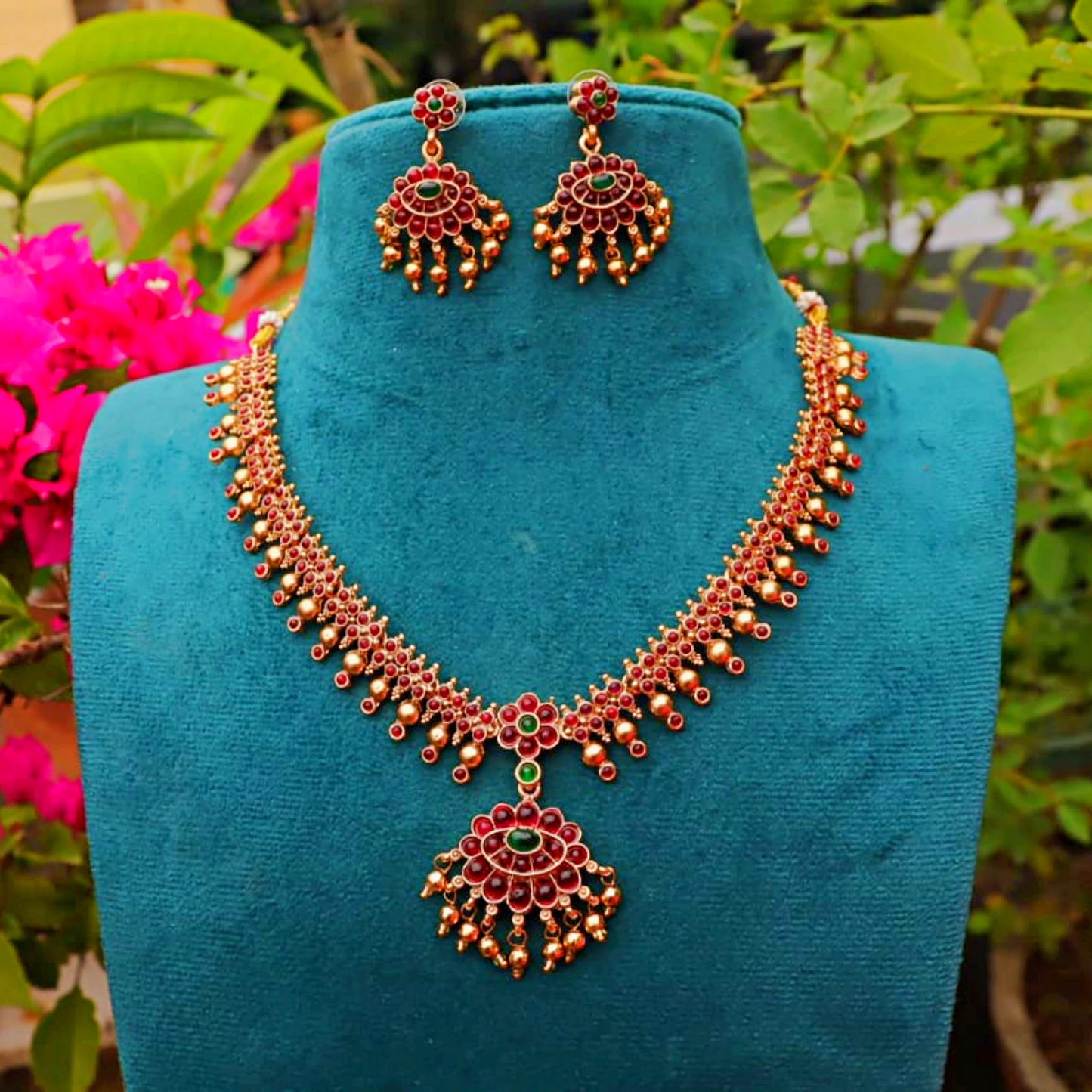 Ornate necklace and earrings on a blue mannequin with a garden background
