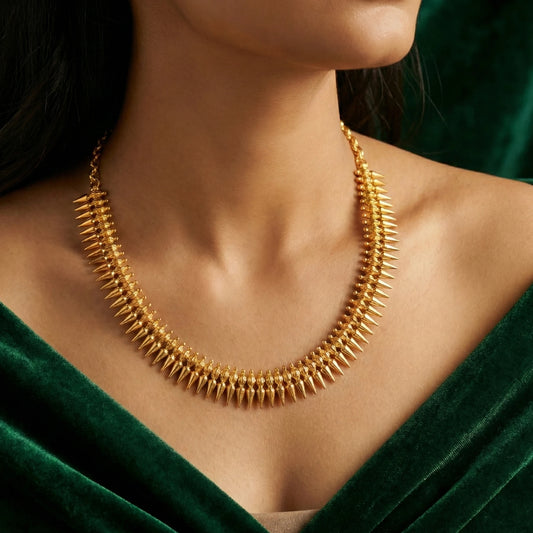Gold plated necklace worn by a person with a green top