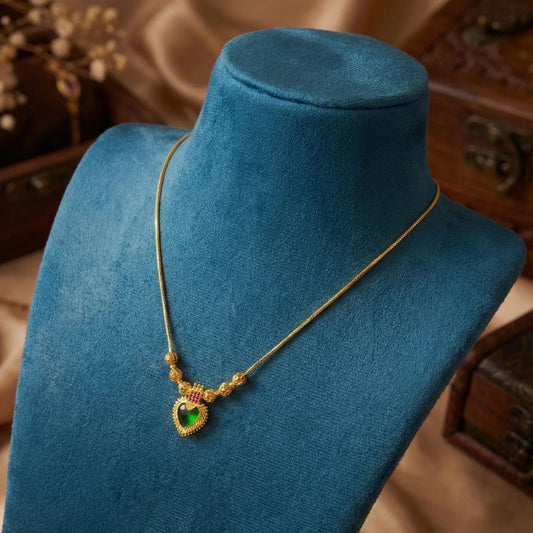 Gold Plated necklace with a green palakka pendant on a blue velvet stand.